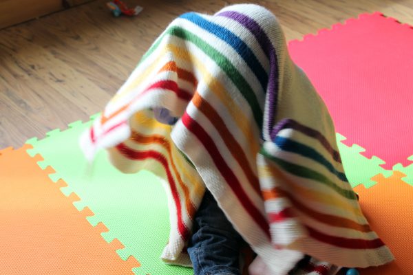 A square baby blanket with rainbow stripes and a seed stitch border