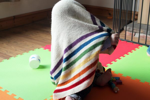 A square baby blanket with rainbow stripes and a seed stitch border