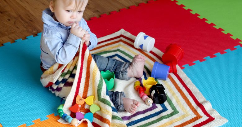 A square baby blanket with rainbow stripes and a seed stitch border