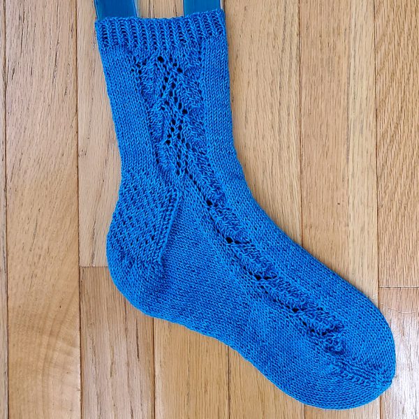 An blue sock with a lace leaf pattern up the outside of the foot