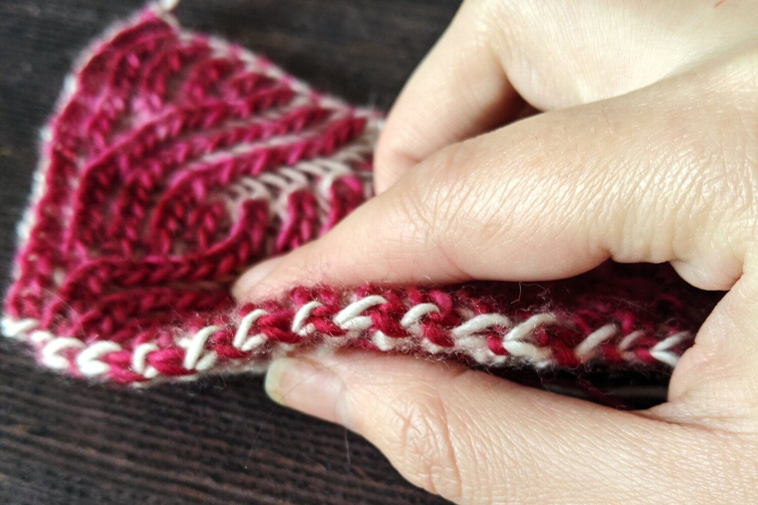 A close up on the completed two colour brioche bind-off with alternating "v"s of pink and white