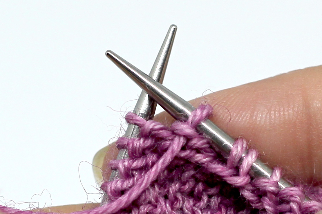 The first stitch from the left-hand needle has been slipped to the right hand needle