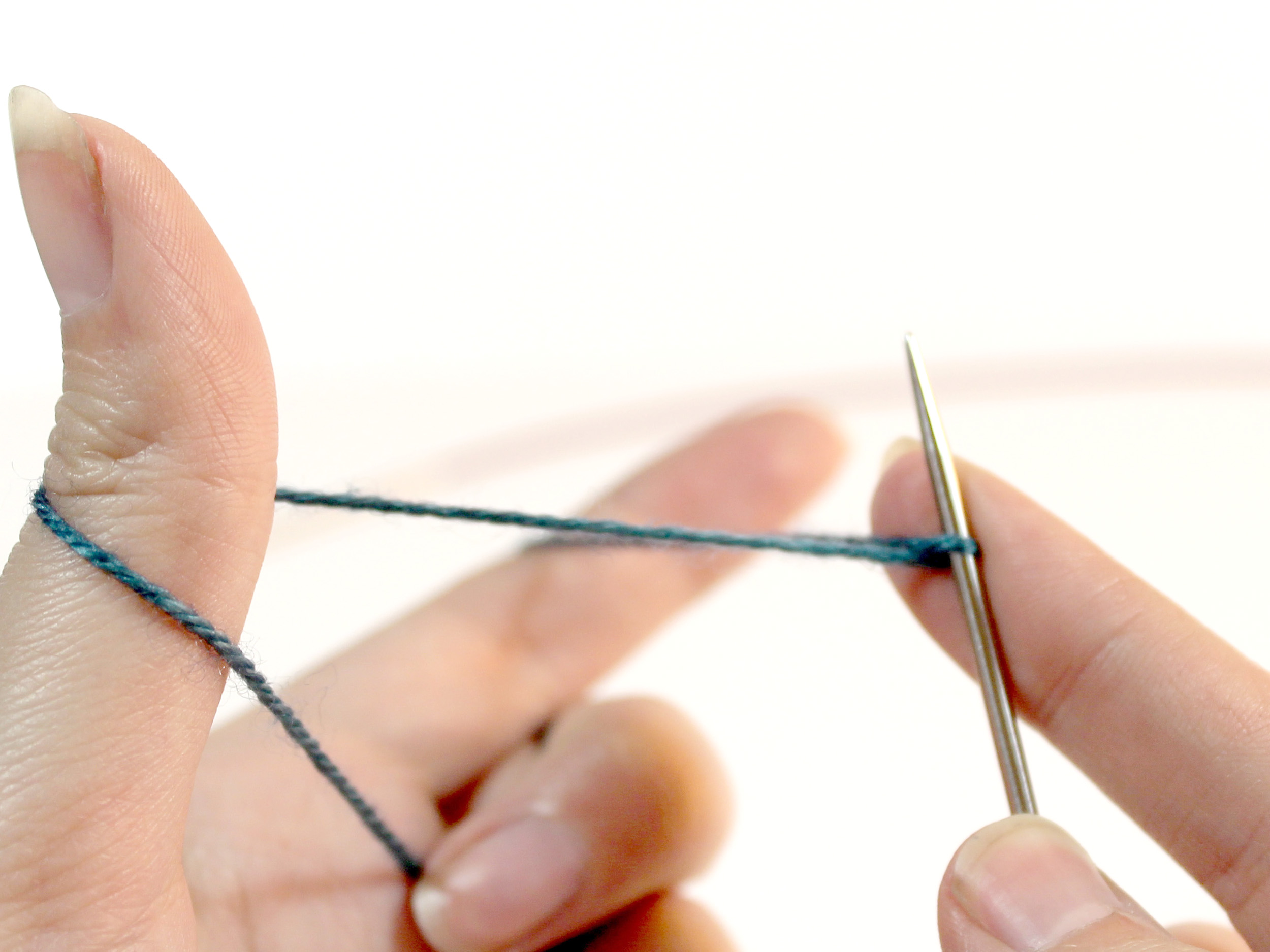 A knitting needle with a twist of yarn that comes from the strand between the thumb and index finger.