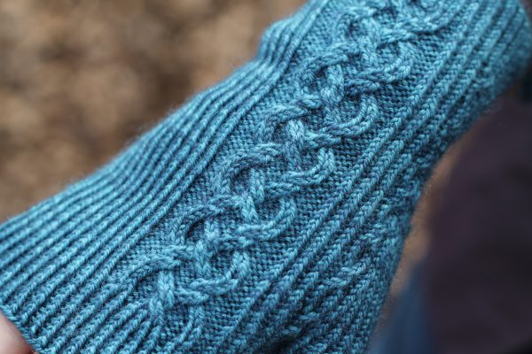 Twisted rib fingerless mitts with a large cable up the back of the hand and a narrow cable pattern that splits around the thumb