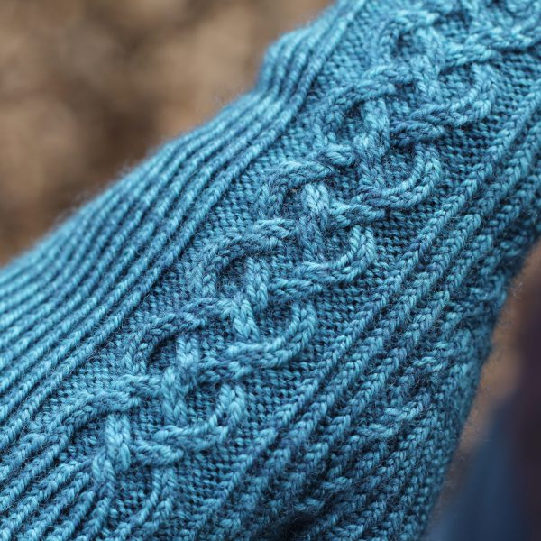 Twisted rib fingerless mitts with a large cable up the back of the hand and a narrow cable pattern that splits around the thumb