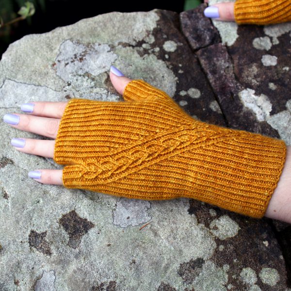 Twisted rib fingerless mitts with a narrow cable crossing the back of the hand from the inside of the wrist to the little finger. The little finger has a separate opening.