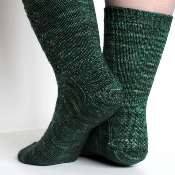 The back of the legs and textured heel pattern of a modelled pair of socks in knit dark green