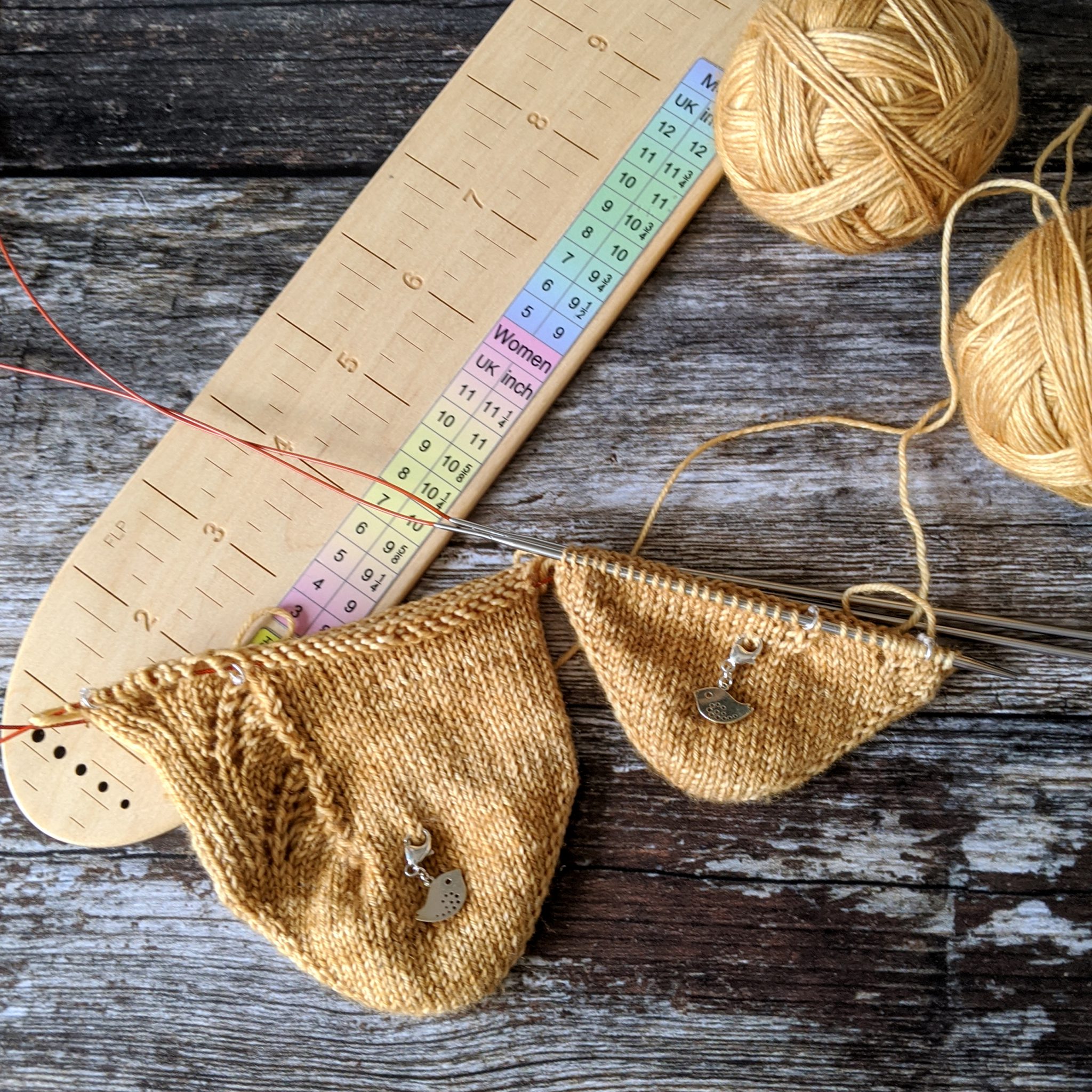 The toes of two socks in progress, the one on the right shows a lace pattern with a visible zigzag line of decreases