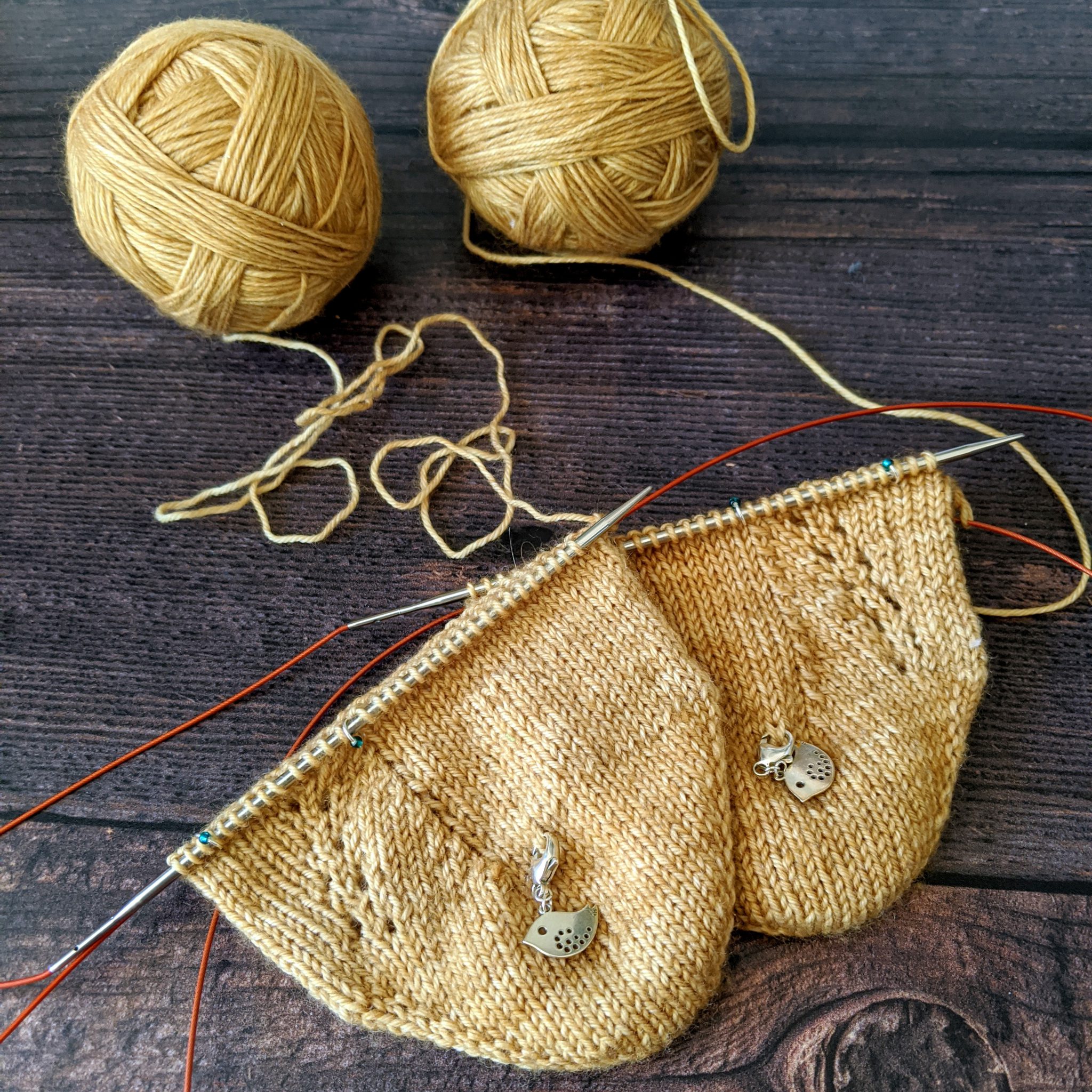 The toes of two socks in progress, they have a lace pattern and subtle vertical line of decreases