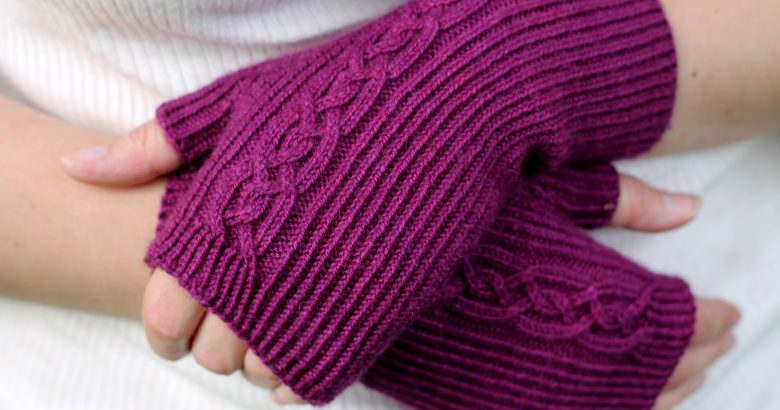 Twisted rib fingerless mitts with a large cable up the back of the hand and a narrow cable pattern that splits around the thumb (hands crossed)