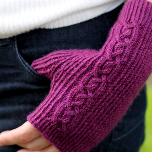 Twisted rib fingerless mitts with a large cable up the back of the hand and a narrow cable pattern that splits around the thumb (thumb tucked into jeans pocket)
