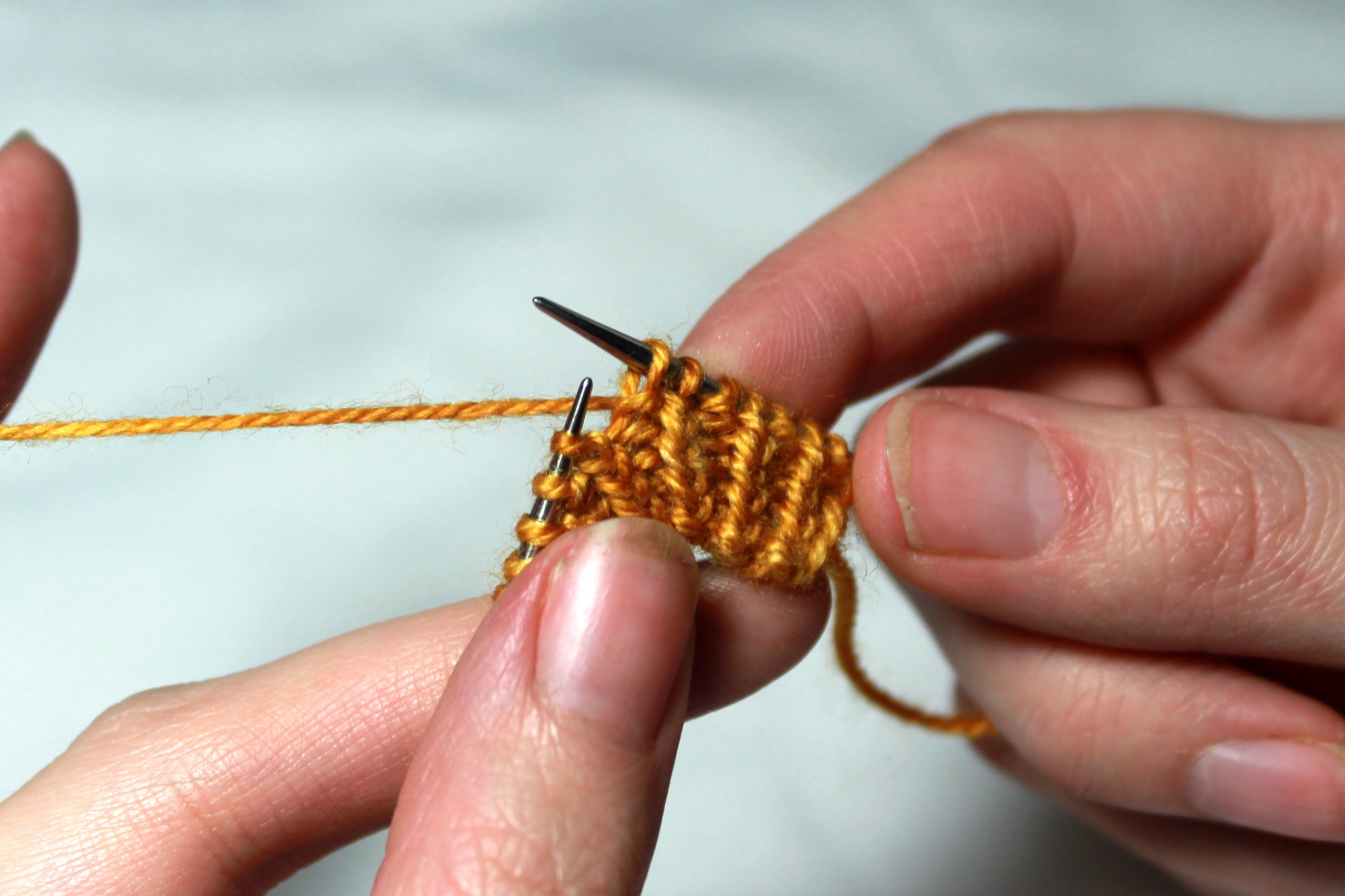 A piece of knitting in twisted rib. A purl stitch has been slipped from the left-hand needle to the right-hand needle