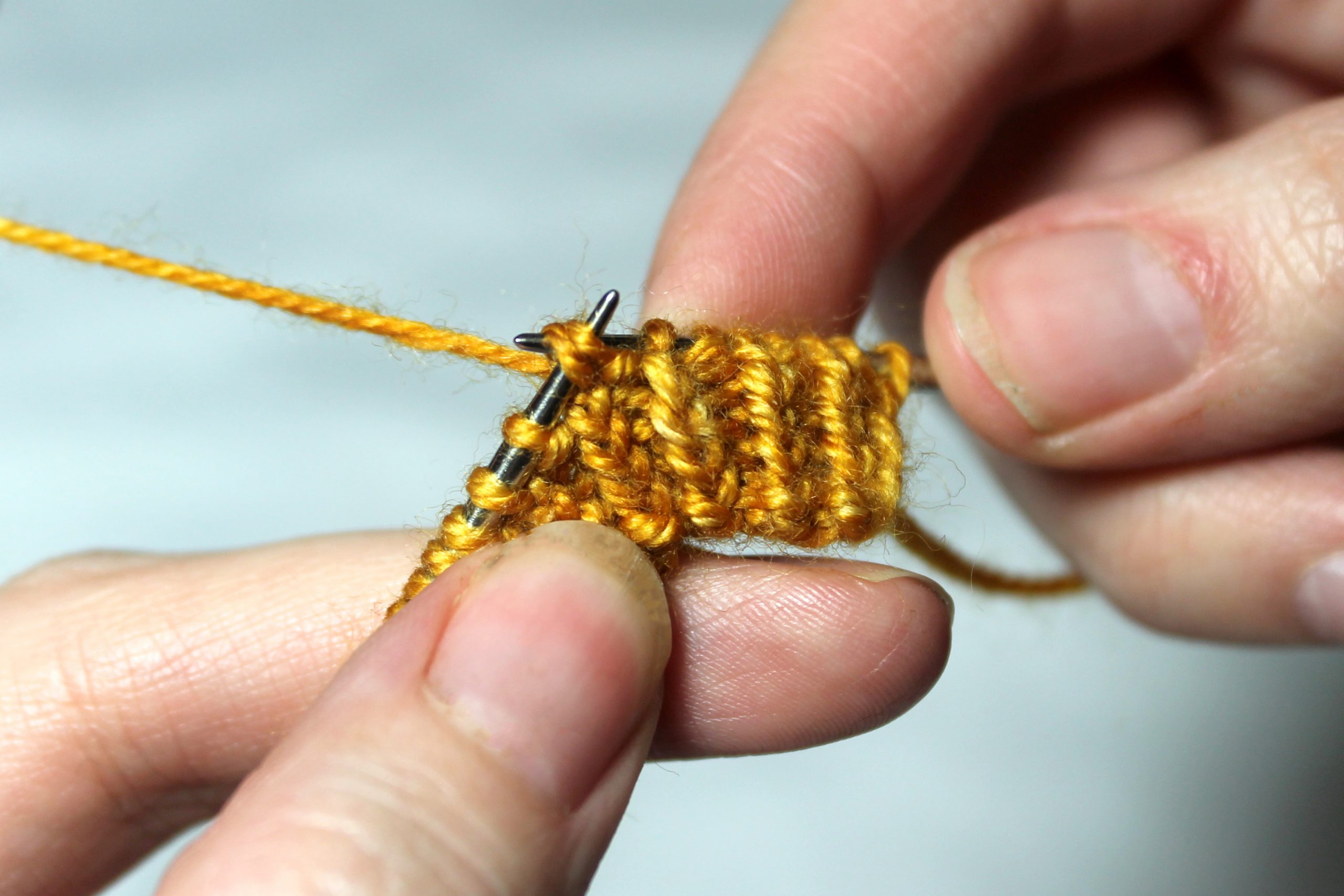 Two stitches are being slipped from the right-hand needle to the left hand needle.