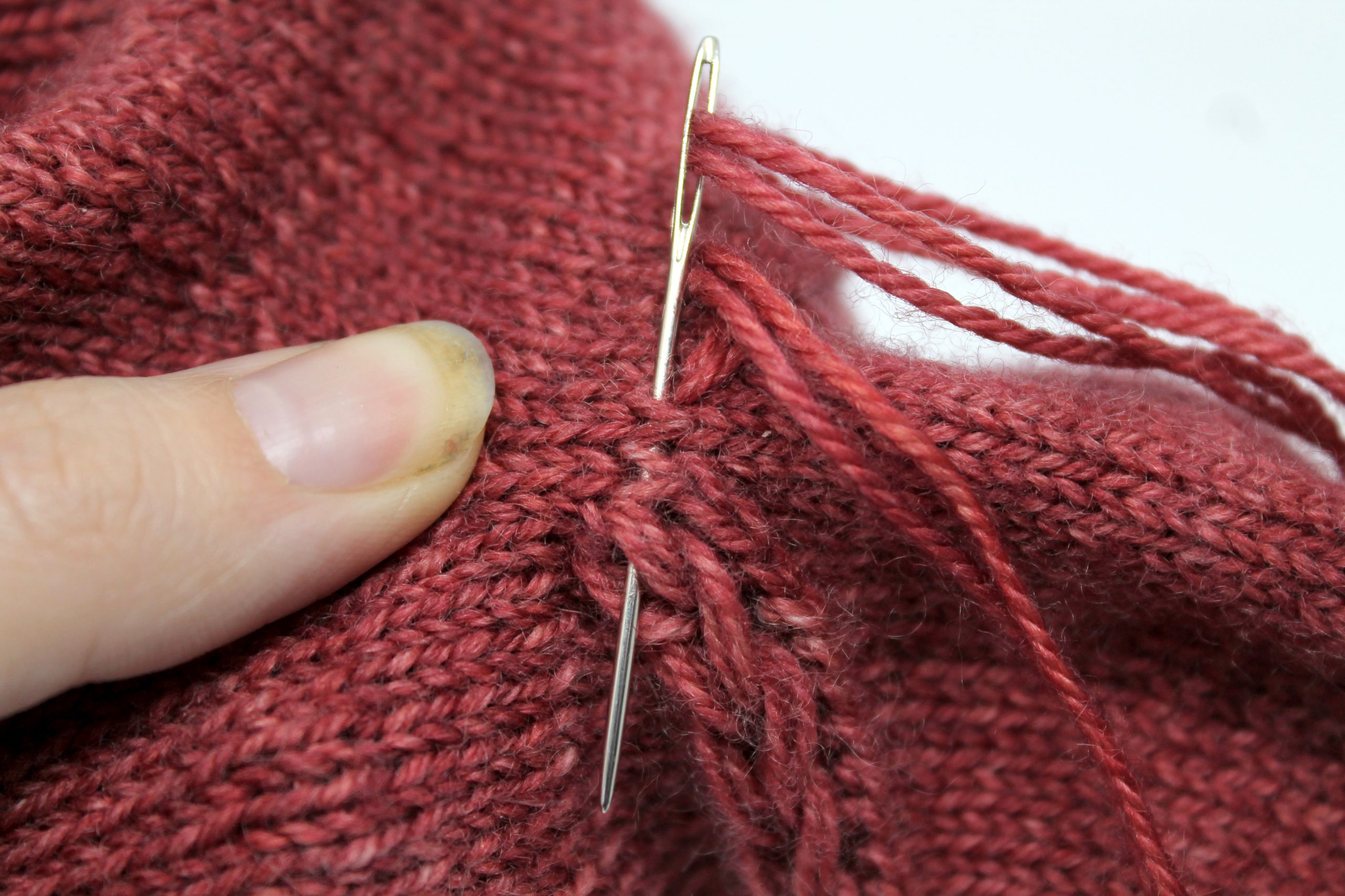 The tapestry need entering the mitt through the fabric and exiting through the last stitch of the drop stitch braid