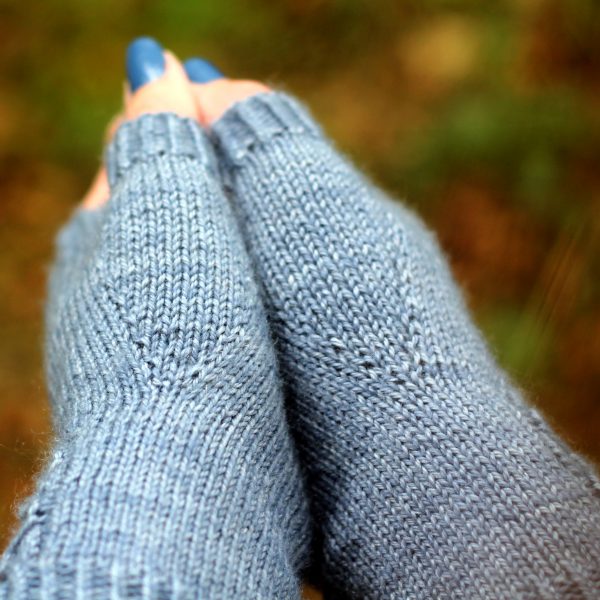 The thumb gussets of a pair of blue fingerless mitts