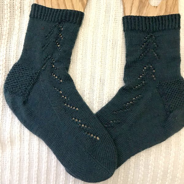 A pair of Giuthas socks knit in dark blue yarn on sock blockers
