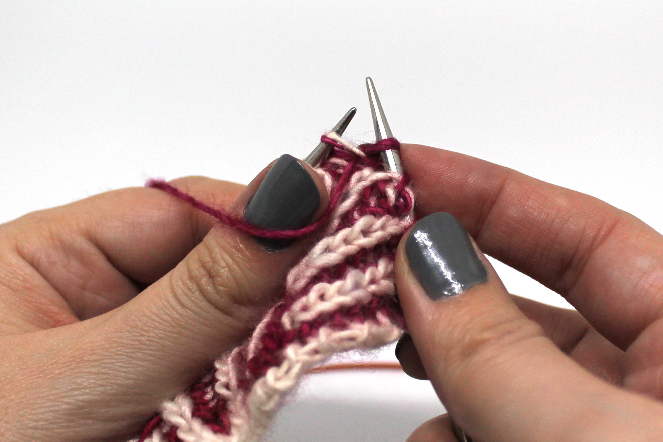 A stitch on the left hand needle with a purl stitch through it on the right hand needle