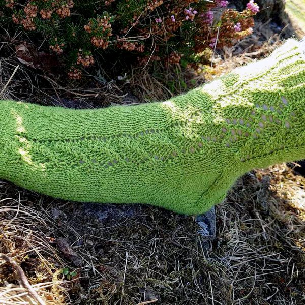 A green sock with a lace leaf pattern up the outside of the foot