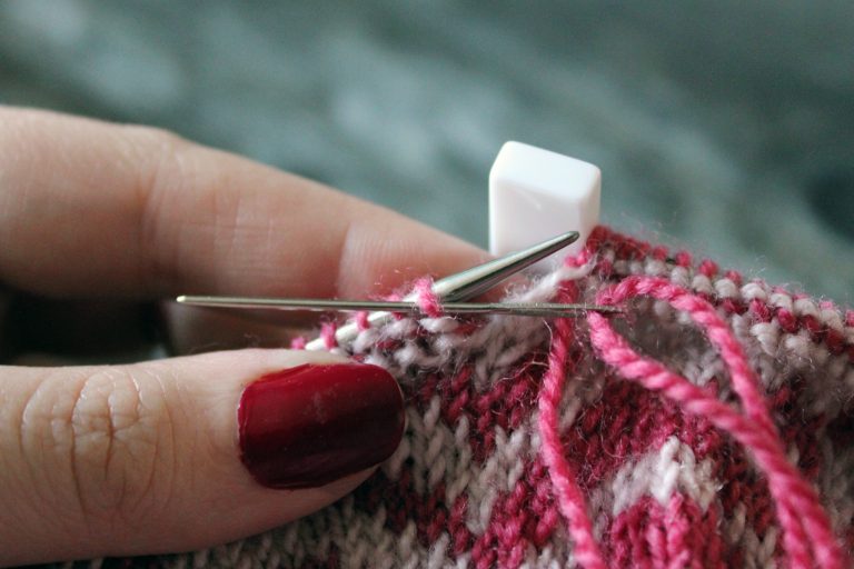 The tapestry needle has been inserted purlwise into the first stitch on the front needle