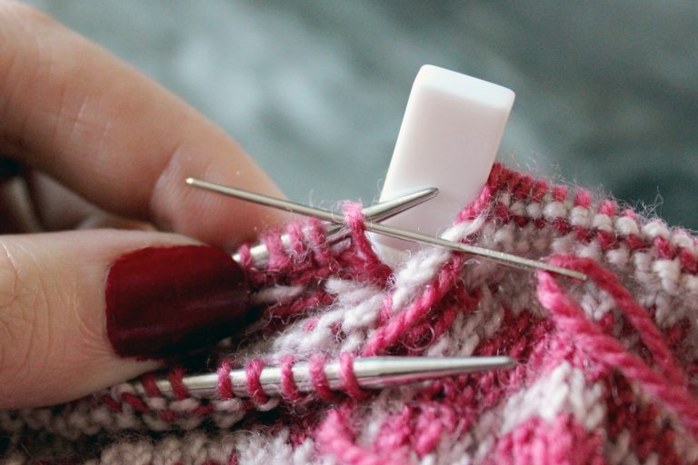 The tapestry needle has been inserted purlwise into the first stitch on the back needle