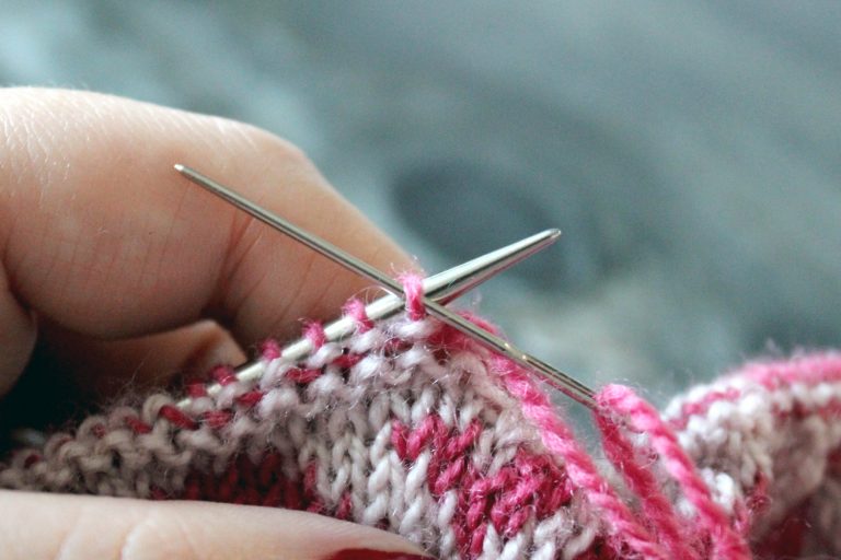 The tapestry needle has been inserted purlwise into the first stitch on the front needle