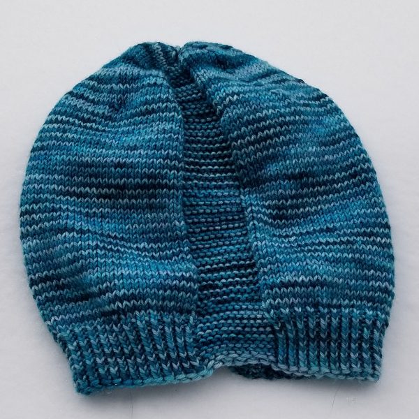 A hat knit in shades of blue with two garter stitch columns laid flat