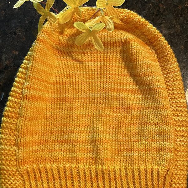 A hat knit in shades of yellow with two garter stitch columns laid flat