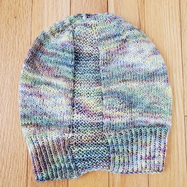 A hat knit with pastel colours and two garter stitch columns laid flat