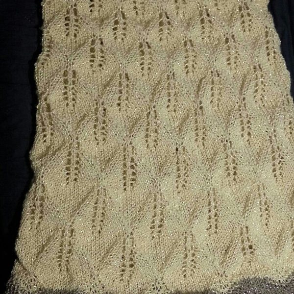 A pale yellow coloured cowl with sparkling yarn, with diamond shaped lace leaves and wide garter stitch borders laid flat