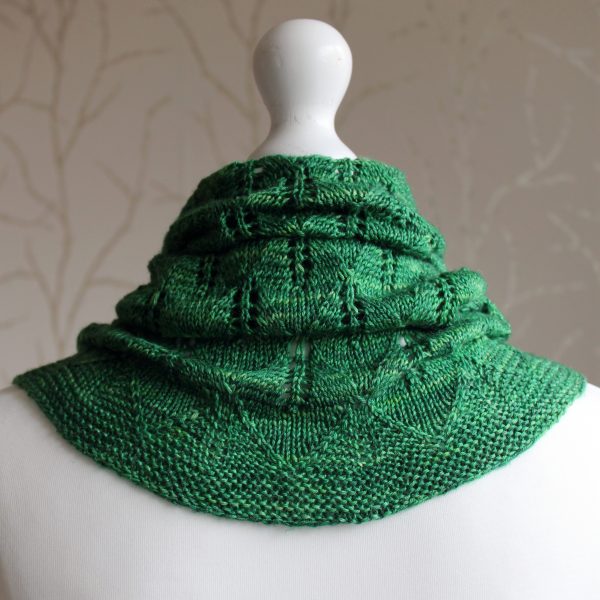 The back of a green cowl with diamond shaped leaves and a wide lace border modelled on a mannequin