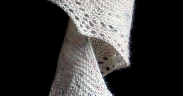 The corner of a shawl hanging down in a spiral showing the garter stitch lace edge