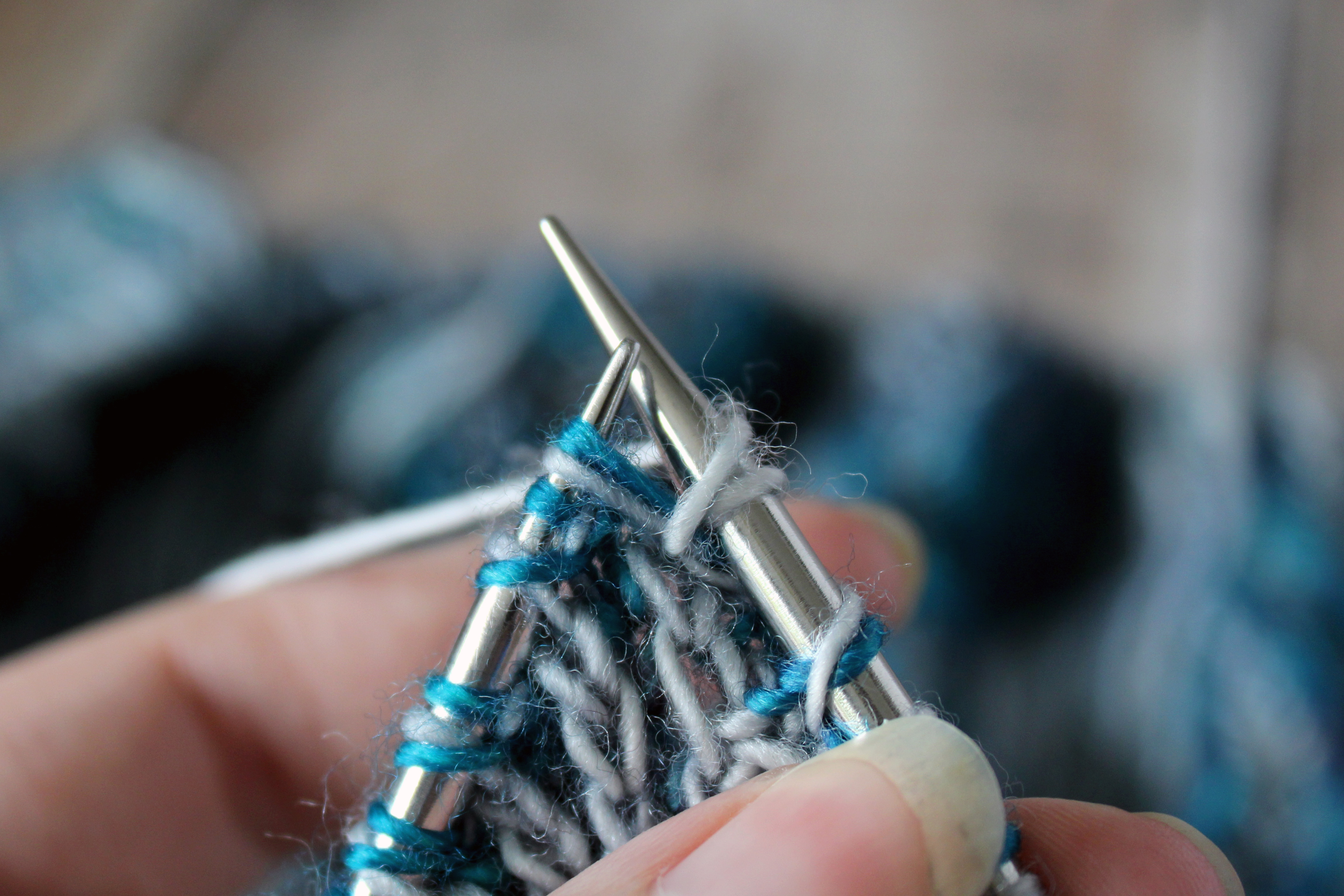 The right needle with a purl stitch and yarn over, the left needle still holds the original stitch.