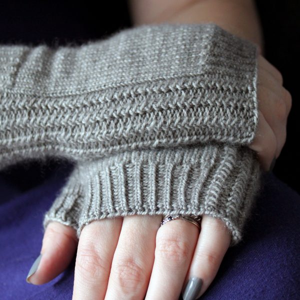 Two fingerless mitts with a twisted rib cuff and a textured rib pattern up both sides, knitted in grey yarn.