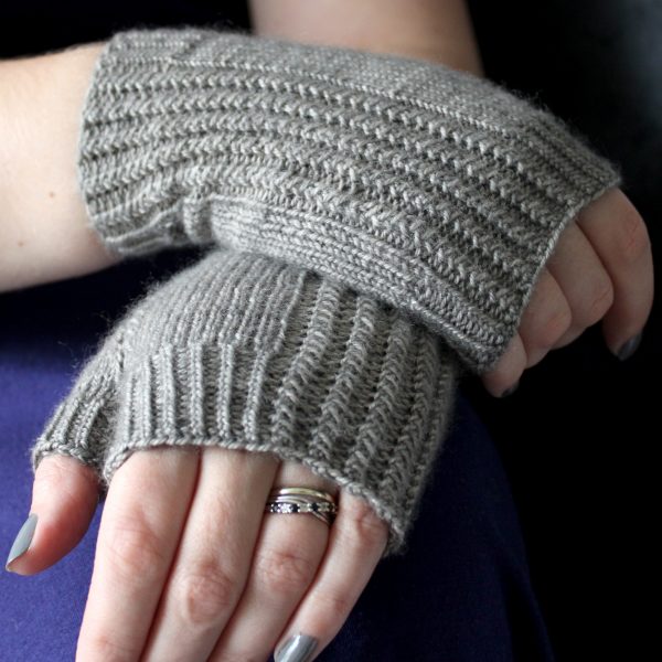 Two fingerless mitts with a twisted rib cuff and a textured rib pattern up both sides, knitted in grey yarn.