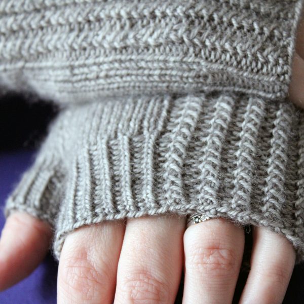Two fingerless mitts with a twisted rib cuff and a textured rib pattern on the back of the hand, knitted in grey yarn.