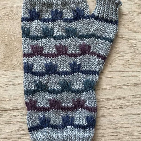 A fingerless mitt with coloured stripes and slipped stitches