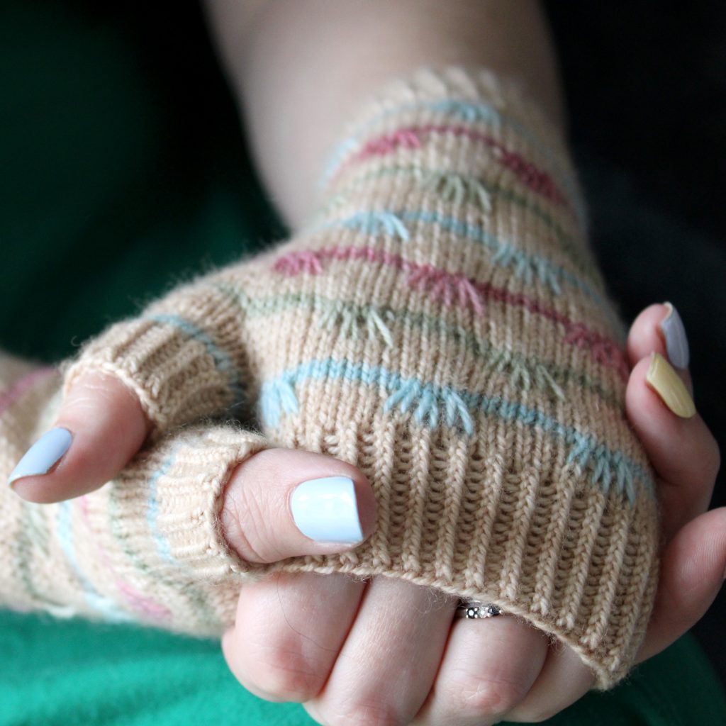 A pair of mitts with coloured stripes and slipped stitches on the back of the hand