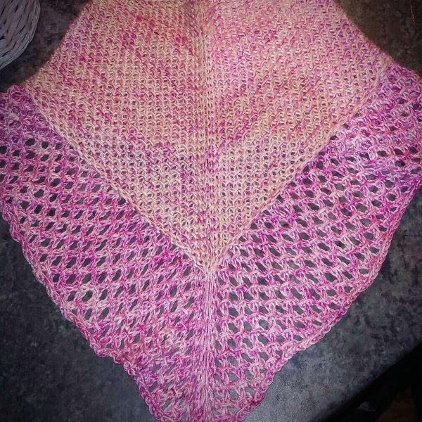 A cowlette with a textured body and lace border knit in pink yarn