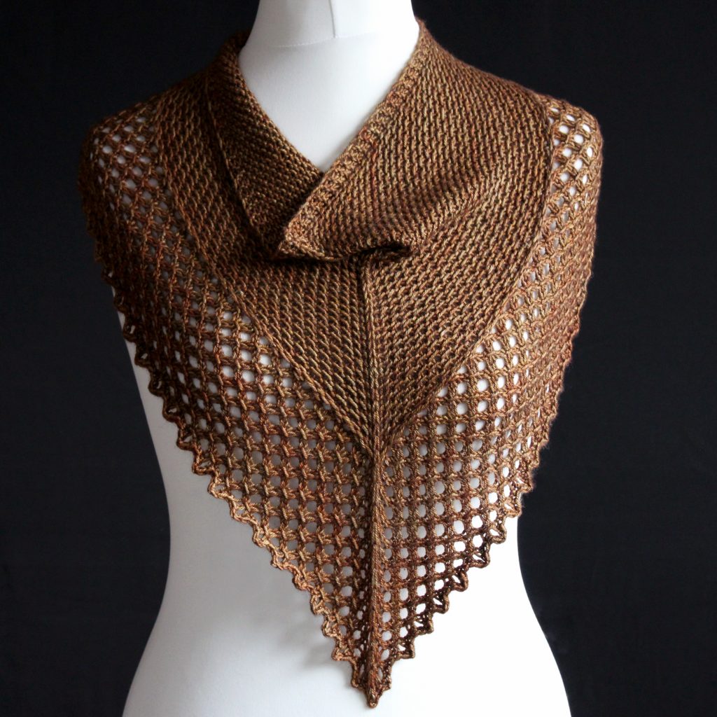 A cowlette knit in brown yarn with a textured slipped stitch pattern on the body, a wide lace border and a rippling bind-off