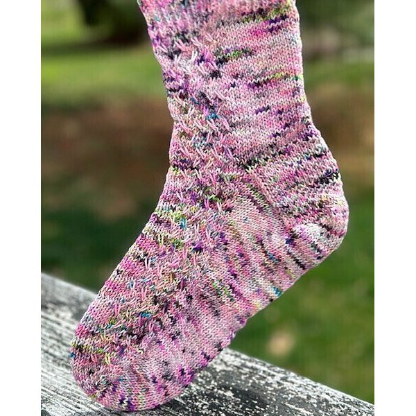 A sock with a rippling cable pattern up the side, knit in pink speckled yarn