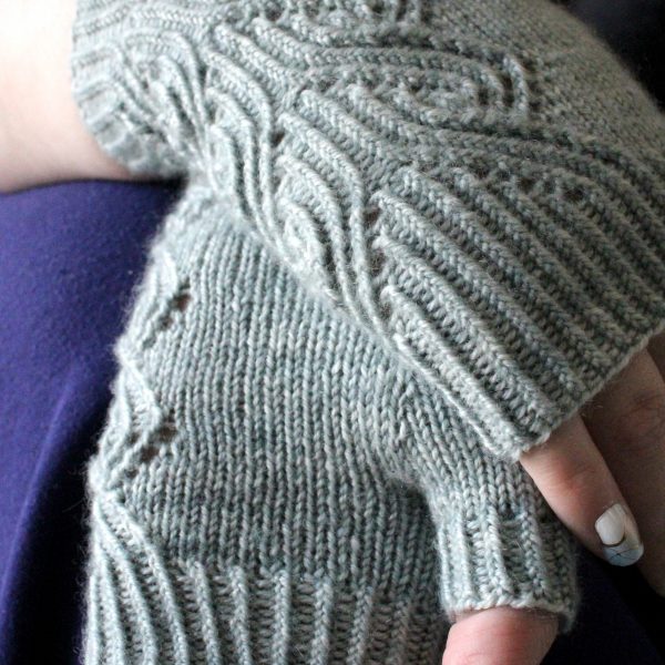 A pair of fingerless mitts with a twisted rib and lace faux cable pattern, knit in a pale blue yarn
