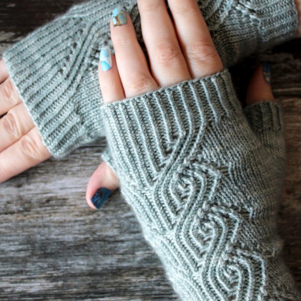 A pair of fingerless mitts with a twisted rib and lace faux cable pattern, knit in a pale blue yarn