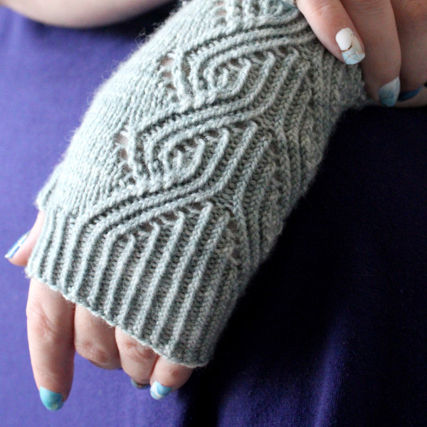 A pair of fingerless mitts with a twisted rib and lace faux cable pattern, knit in a pale blue yarn