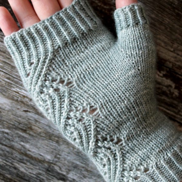 The palm of a fingerless mitt with a twisted rib and lace faux cable pattern, knit in a pale blue yarn