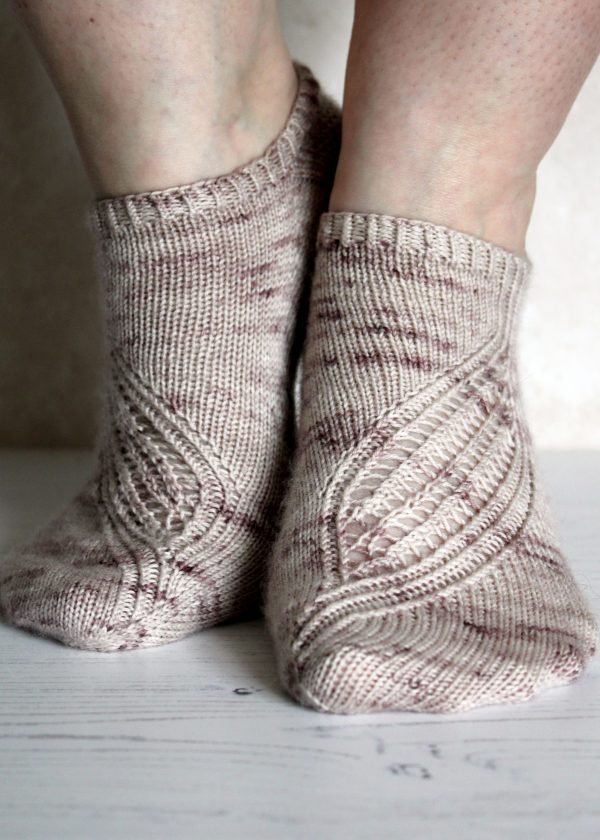 Trainer socks with a lace and twisted rib pattern travelling across the sock. The socks are knit in light brown yarn with speckles.