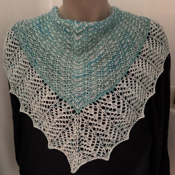 A cowlette with a mosaic body, knit in green and white yarn, with a wide lace border knit in white.