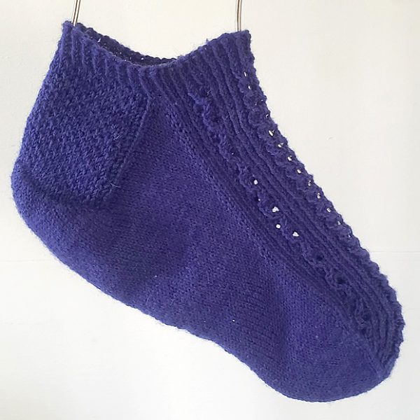 One short (trainer) socks with a twisted rib and lace pattern covering the top of the foot. The sock is knit in purple yarn.